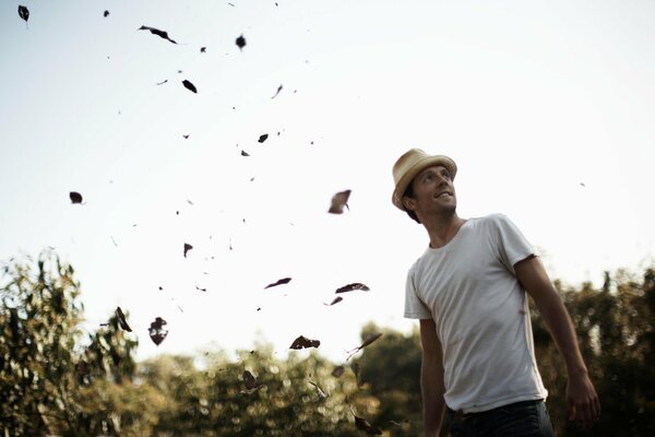 El chico con el sombrero en el fondo de la caída de las hojas