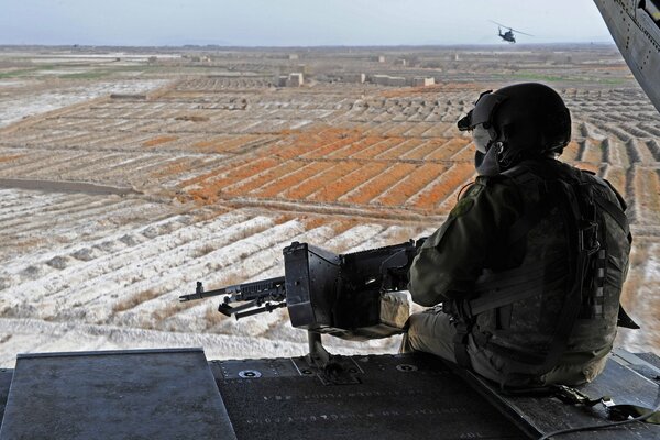 Un soldado con una ametralladora mirando hacia el horizonte