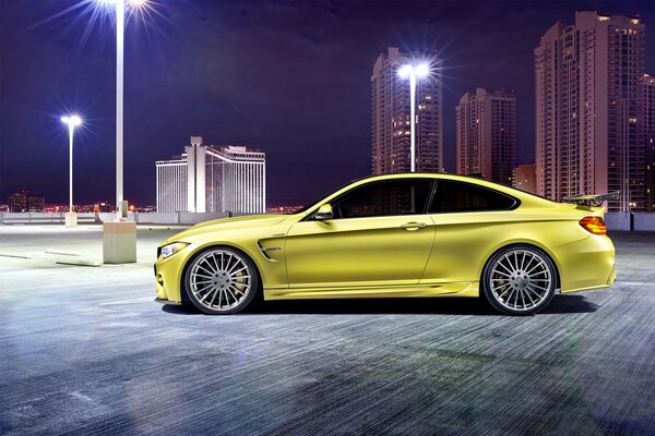BMW M4 amarillo en el fondo de la ciudad nocturna