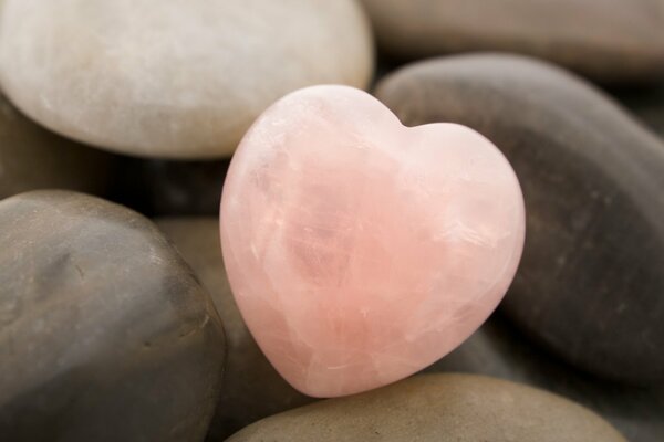 Corazón de piedra de color rosa entre las piedras comunes