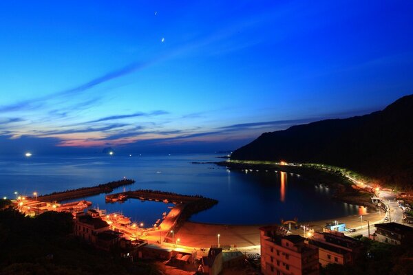 Ciudad nocturna junto al mar. Atardecer