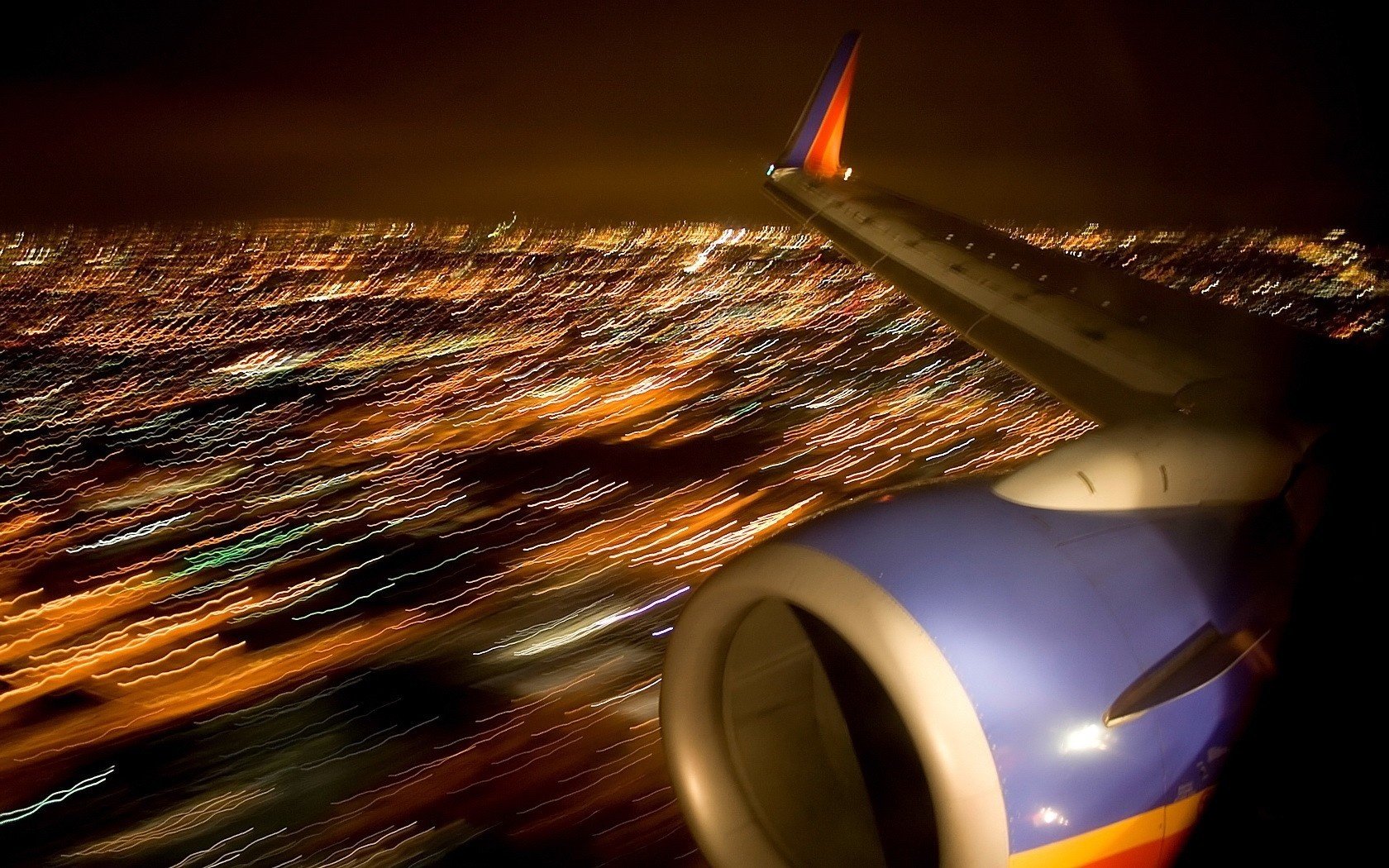 vista borrosa ala de avión vuelo en la noche turbina luces de la ciudad aviones aviación transporte aéreo