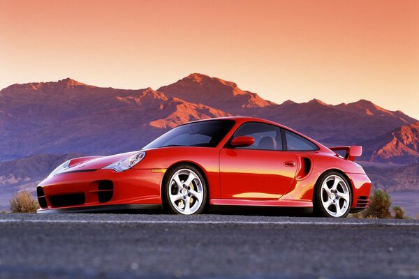 En el fondo de las montañas hay un hermoso coche rojo