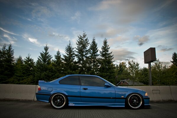 Azul afinado BMW E36 en el fondo del bosque