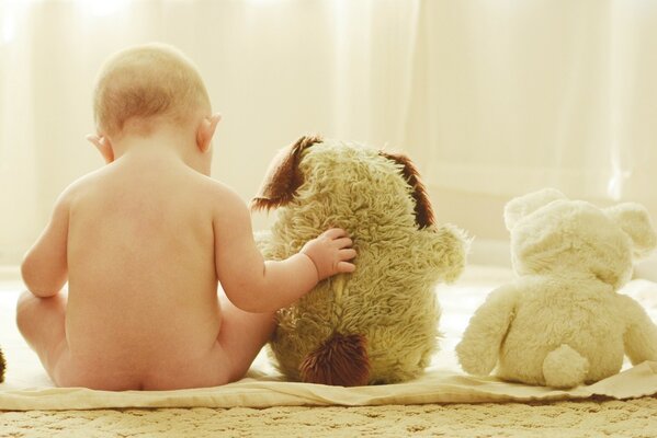 Bebé sentado en una fila con juguetes blandos
