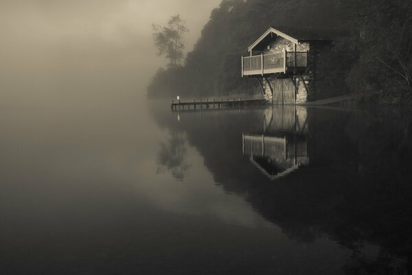 Lago en la niebla con una casa solitaria