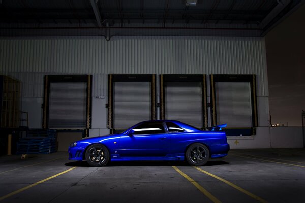 Un automóvil Nissan R34 de color azul se encuentra a oscuras en la calle
