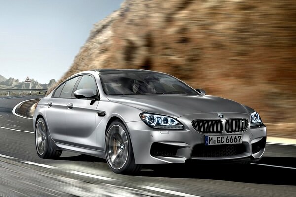 El bmw M6 gran coupé conduce a gran velocidad en terrenos montañosos