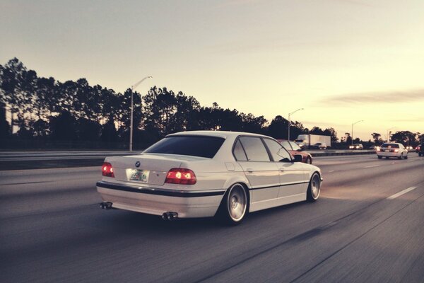 BMW E38 blanco a toda velocidad en la carretera
