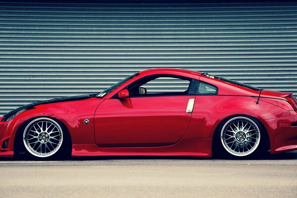 Foto de un nissan 350Z rojo en el fondo de una persiana enrollable cerrada