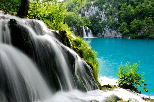 Cascada de montaña que desemboca en el lago azul