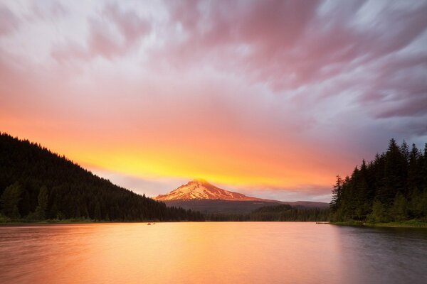 Lago al atardecer y montañas en las nubes