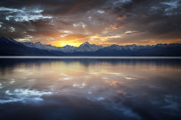 Reflejo de las nubes en el lago en el fondo de los picos nevados