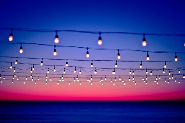 Líneas de alambre decoradas con lámparas en el fondo de la puesta de sol