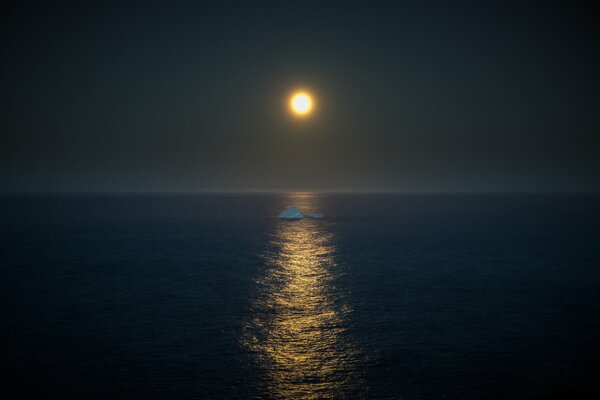 En medio del mar, a la luz de la Luna llena, un iceberg flota