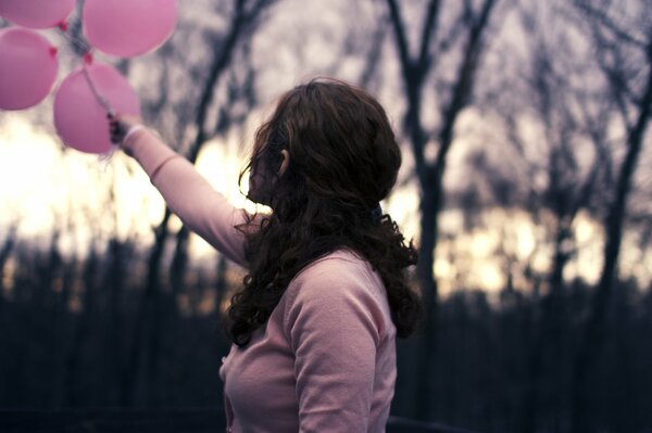 Chica sostiene globos de color rosa detrás de ella son un fondo borroso