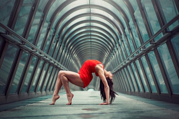 Gimnasta chica en rojo con una hermosa figura y piernas delgadas