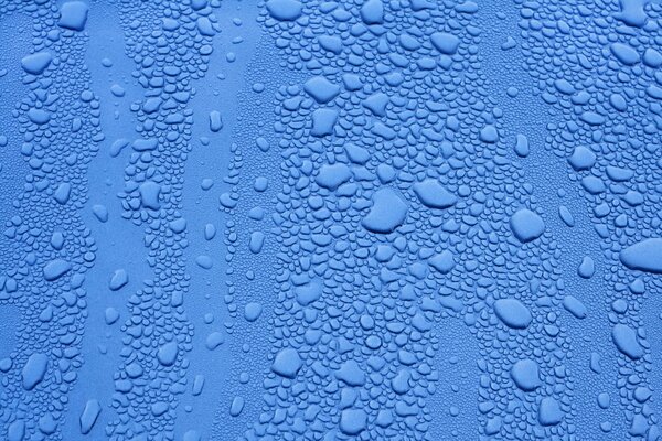 Gotas de diferentes tamaños en la superficie azul