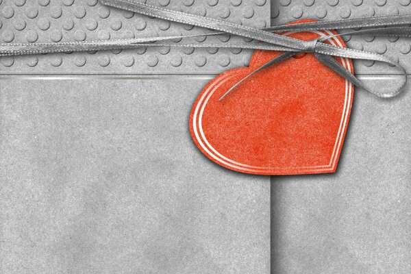 Postal gris atada con cinta con corazón rojo