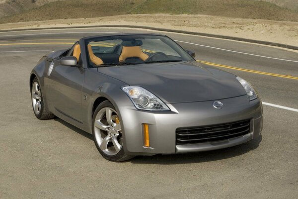 El automóvil Nissan plateado está parado en la carretera