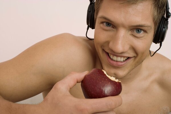 Hombre con auriculares come manzana