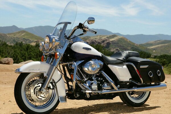 Harley blanco-guapo en el fondo de las montañas y el cielo