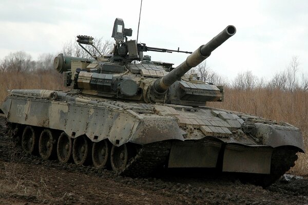 Un tanque militar monta en un camino fangoso