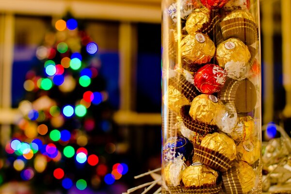 Una lata de dulces en primer plano y un árbol de Navidad decorado en la parte posterior