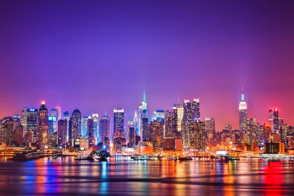 Las luces de la noche de Manhattan se reflejan en el río Hudson