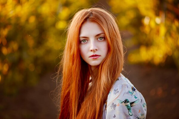 Retrato de otoño de una chica pelirroja con un fondo borroso