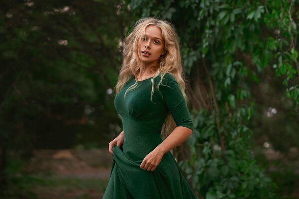 Chica con un vestido verde en el fondo del follaje