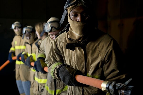 Cinco bomberos mantienen una manguera