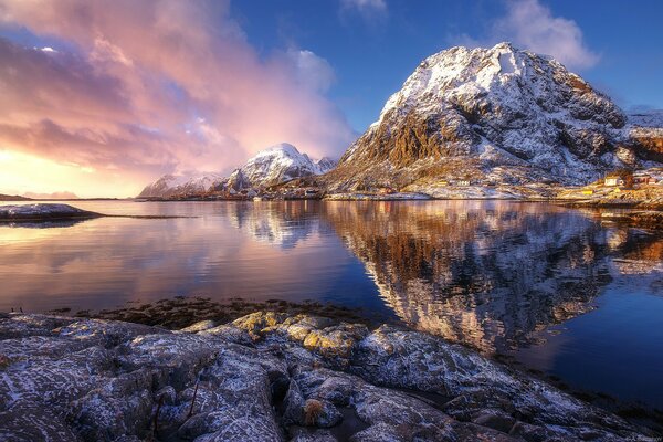 La puesta de sol rosa y las rocas nevadas se reflejan en el agua azul
