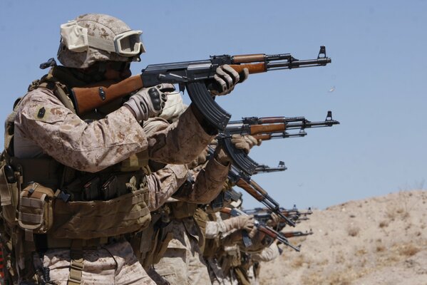 Soldados con equipo disparan Kalashnikov