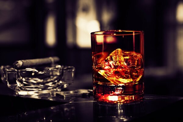 Sobre la mesa un vaso de whisky con hielo