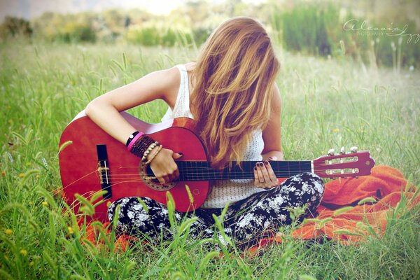 Chica con guitarra sentada en la hierba