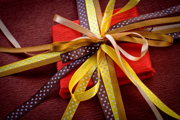 Caja de regalo cuadrada roja atada con cintas amarillas