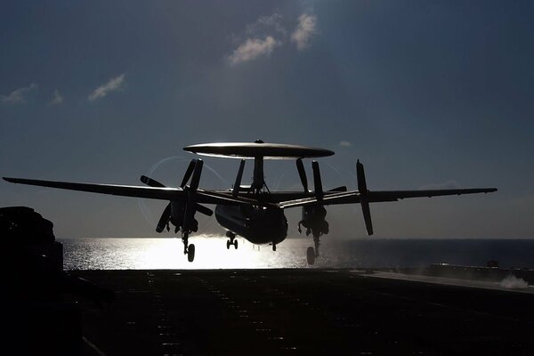 Un portaaviones y un avión al atardecer