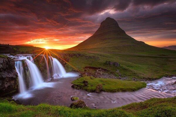 Cascada y volcán en Islandia con puesta de sol