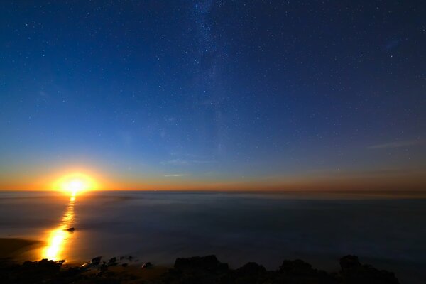 Amanecer en el cielo estrellado sobre el océano