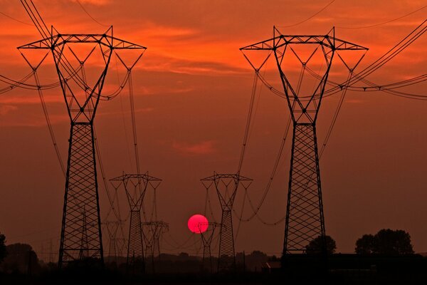 Siluetas de soportes de líneas eléctricas al atardecer