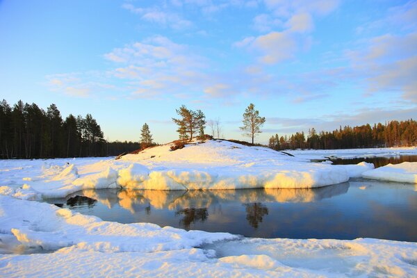 Río y bosque de invierno contra el cielo azul