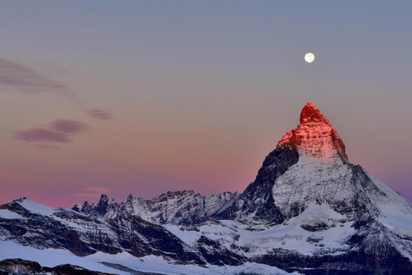 La cima de los Alpes contra el cielo crepuscular. Luna sobre la cima